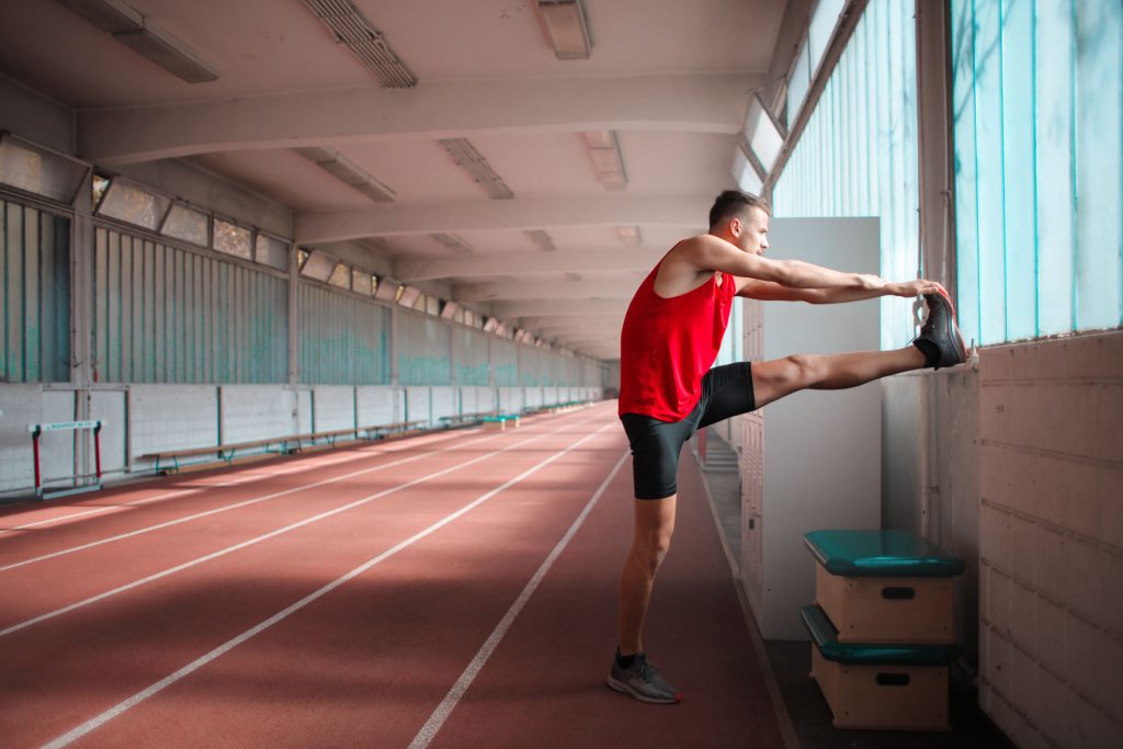 atleet rekt zijn benen op een sportbaan