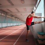 atleet rekt zijn benen op een sportbaan