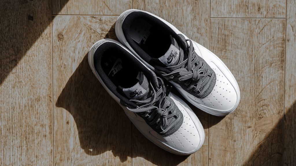 Paar witte sneakers van bovenaf op een houten vloer