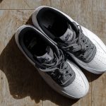 Paar witte sneakers van bovenaf op een houten vloer