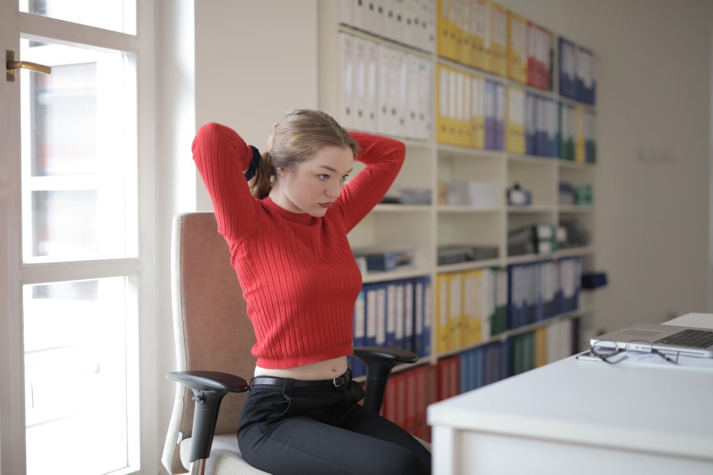 Vrouw in rode trui strekt zich uit aan bureau